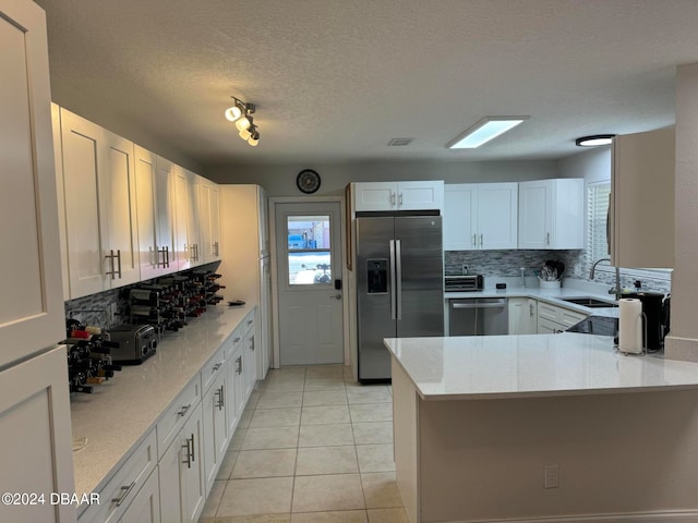 kitchen featuring backsplash, white cabinetry, kitchen peninsula, and appliances with stainless steel finishes