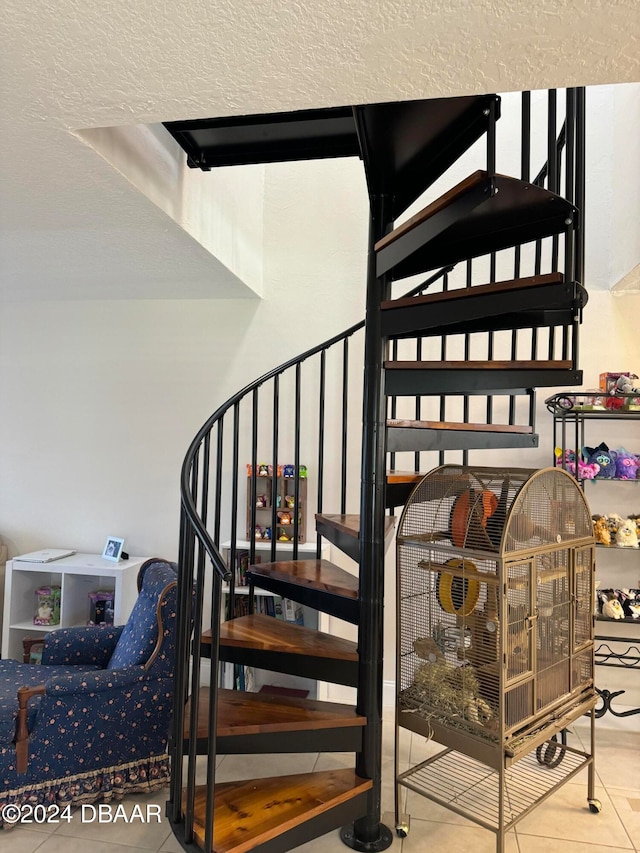 staircase with tile patterned flooring and a textured ceiling