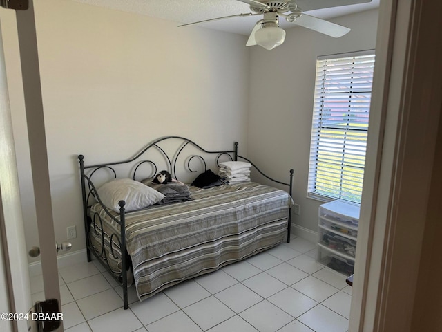 tiled bedroom featuring multiple windows and ceiling fan