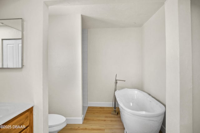 33 Sea Harbor Dr E, Ormond Beach, FL 32176 - bathroom with wood finished floors, vanity, a soaking tub, toilet, and baseboards