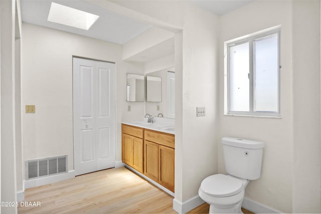 33 Sea Harbor Dr E, Ormond Beach, FL 32176 - bathroom with a skylight, toilet, wood finished floors, and baseboards