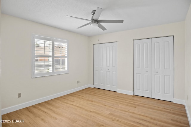 33 Sea Harbor Dr E, Ormond Beach, FL 32176 - unfurnished bedroom featuring two closets, light wood-type flooring, baseboards, and a ceiling fan