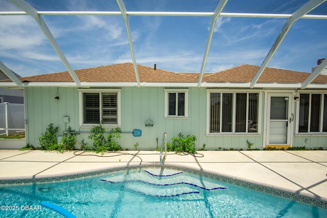 33 Sea Harbor Dr E, Ormond Beach, FL 32176 - back of property featuring board and batten siding, a patio, roof with shingles, a lanai, and an outdoor pool
