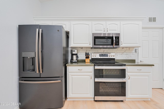 kitchen featuring white cabinets, stainless steel appliances, tasteful backsplash, and light hardwood / wood-style flooring