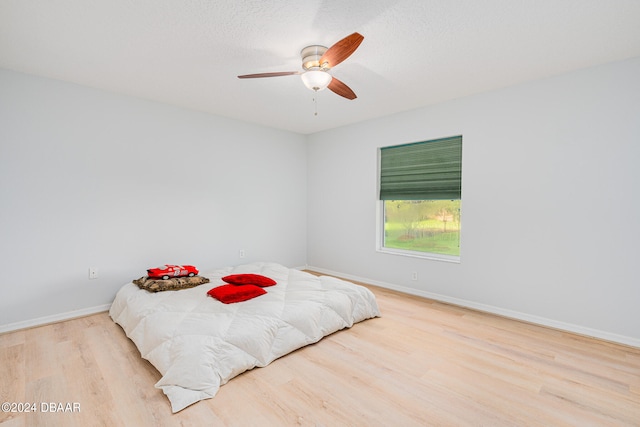 bedroom featuring ceiling fan, a textured ceiling, and light hardwood / wood-style flooring