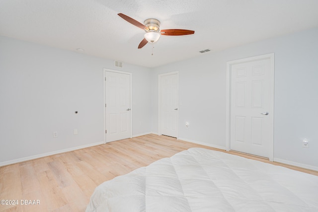 bedroom with a textured ceiling, light wood-type flooring, and ceiling fan