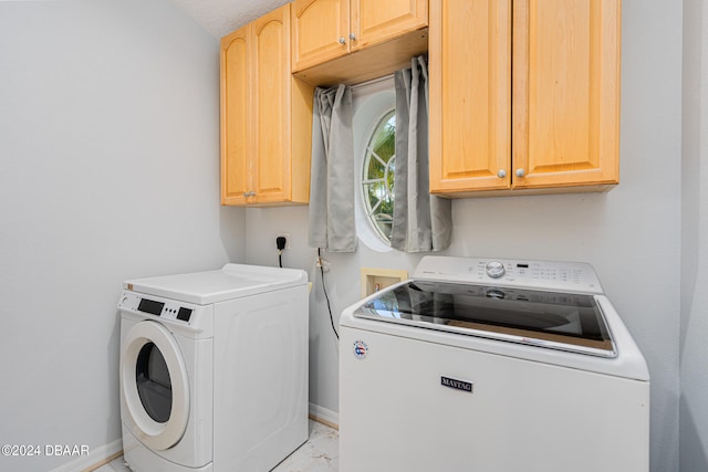 clothes washing area featuring a textured ceiling, washing machine and dryer, and cabinets