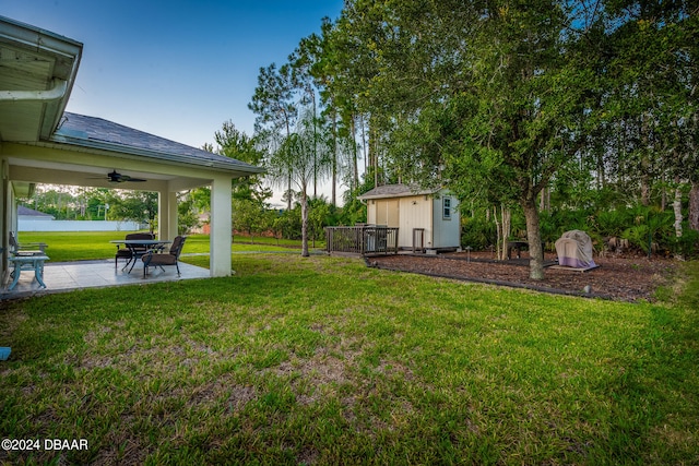 view of yard featuring a shed, ceiling fan, and a patio area