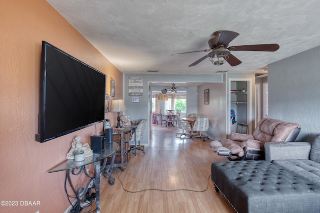 living room with wood-type flooring, ceiling fan, and a textured ceiling