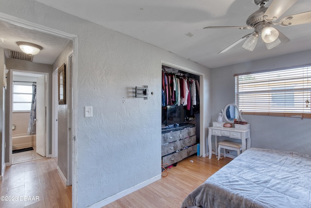 bedroom with light hardwood / wood-style floors, a closet, multiple windows, and ceiling fan