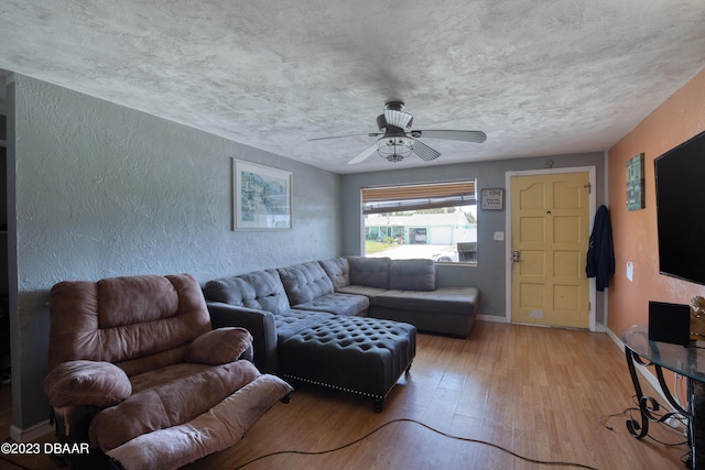 living room with light hardwood / wood-style floors, ceiling fan, and a textured ceiling