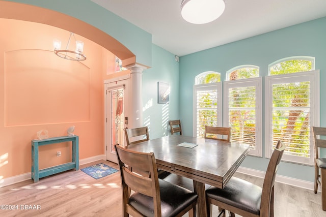 dining area featuring decorative columns, light hardwood / wood-style floors, and a notable chandelier