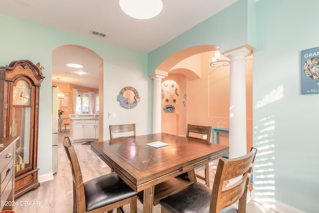 dining area with decorative columns and light hardwood / wood-style floors