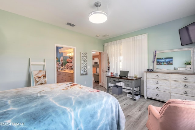 bedroom featuring light wood-type flooring and ensuite bath