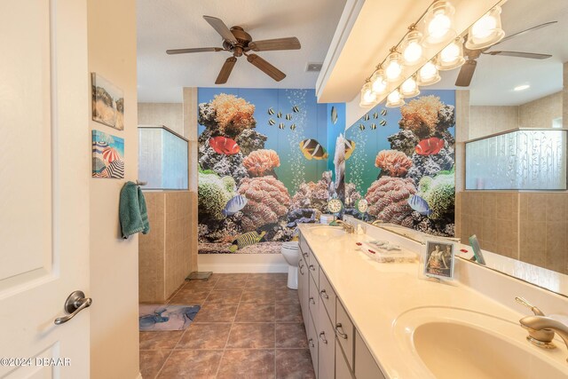 bathroom featuring vanity, tile patterned flooring, toilet, a textured ceiling, and a tile shower