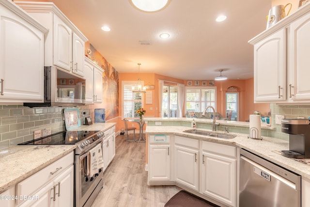 kitchen with white cabinetry, sink, hanging light fixtures, stainless steel appliances, and light hardwood / wood-style flooring