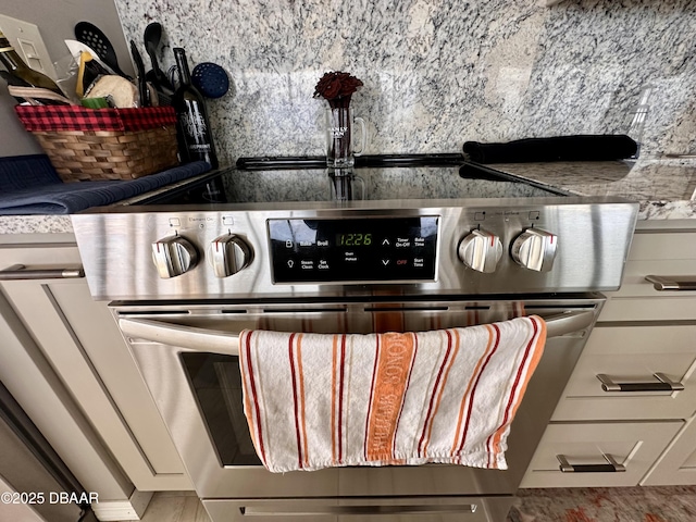 interior details with white cabinetry, tasteful backsplash, and electric range