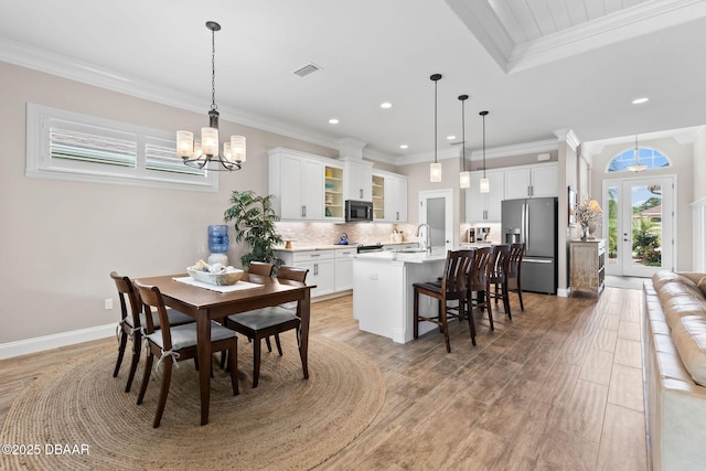 dining area featuring crown molding, visible vents, a notable chandelier, and light wood-style floors