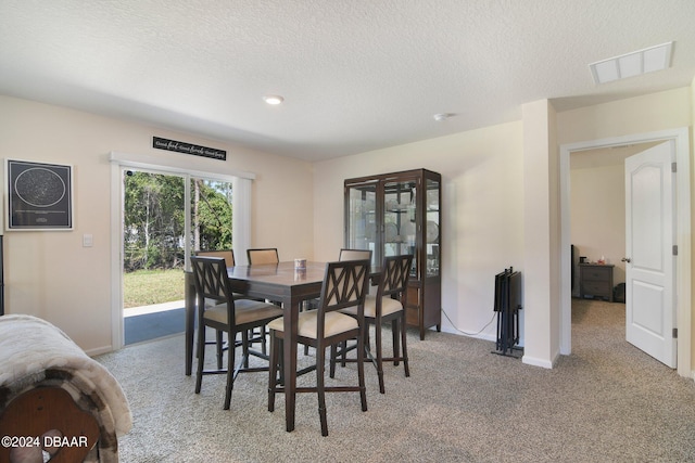 dining room featuring a textured ceiling and light carpet