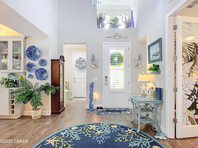 foyer entrance featuring a towering ceiling, hardwood / wood-style floors, and crown molding