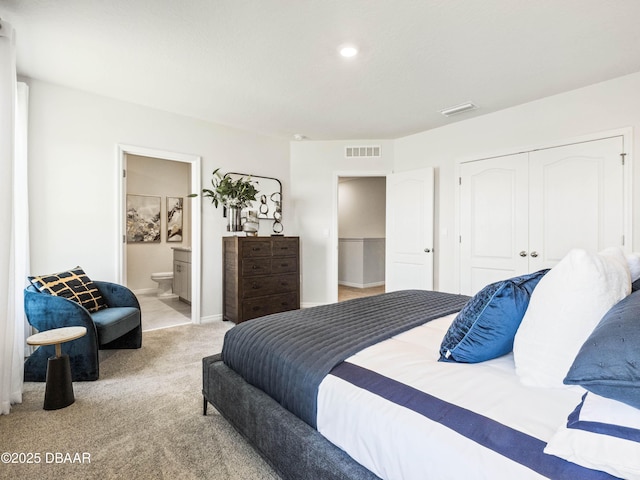 bedroom featuring a closet, ensuite bath, and light carpet