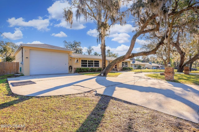 view of front of home featuring a front lawn, concrete driveway, an attached garage, and fence