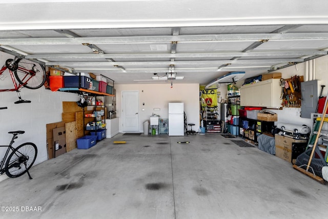 garage with a garage door opener, freestanding refrigerator, and electric panel
