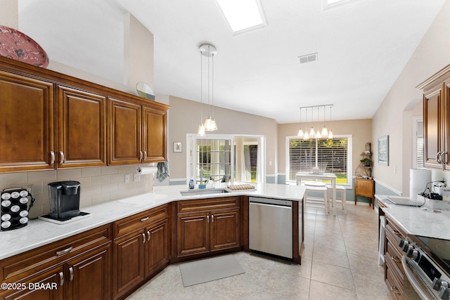 kitchen with a notable chandelier, a sink, appliances with stainless steel finishes, a peninsula, and backsplash