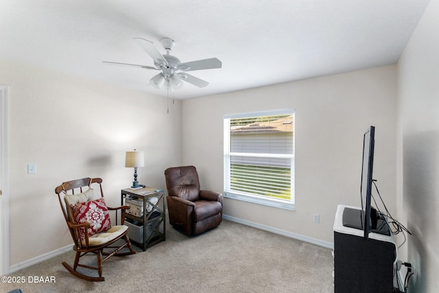 living area featuring carpet flooring, baseboards, and a ceiling fan
