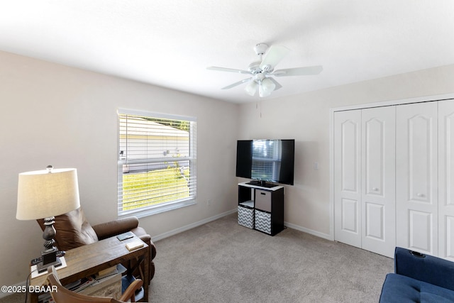 living area featuring light carpet, baseboards, and a ceiling fan