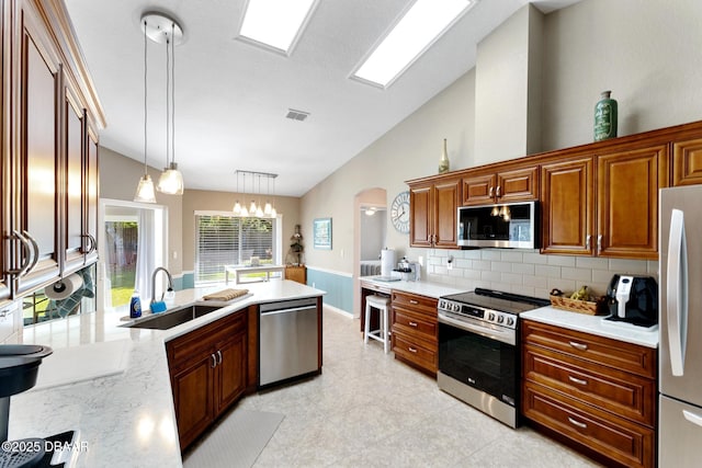 kitchen with visible vents, vaulted ceiling, appliances with stainless steel finishes, a sink, and decorative backsplash