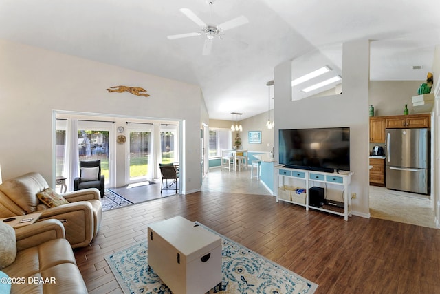 living area featuring ceiling fan with notable chandelier, high vaulted ceiling, wood finished floors, french doors, and baseboards