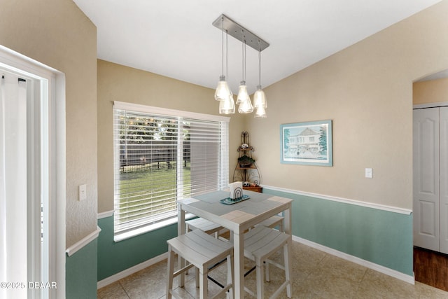 tiled dining area featuring a wealth of natural light, arched walkways, an inviting chandelier, and baseboards