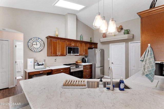 kitchen with hanging light fixtures, a sink, brown cabinetry, stainless steel appliances, and backsplash
