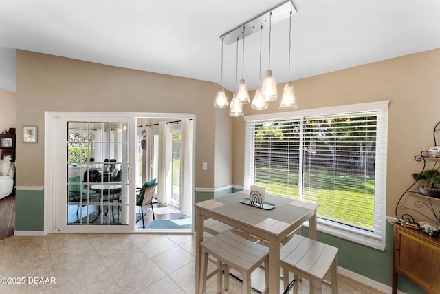 dining area with a chandelier, light tile patterned flooring, baseboards, and plenty of natural light