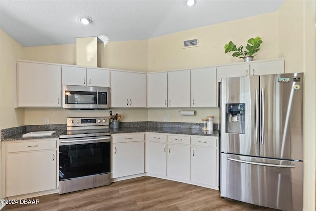 kitchen featuring lofted ceiling, a textured ceiling, appliances with stainless steel finishes, dark hardwood / wood-style flooring, and white cabinetry