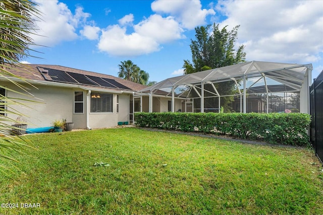 rear view of property with solar panels, a yard, and glass enclosure