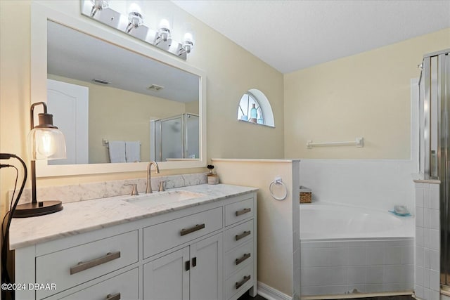 bathroom with vanity, independent shower and bath, and a textured ceiling