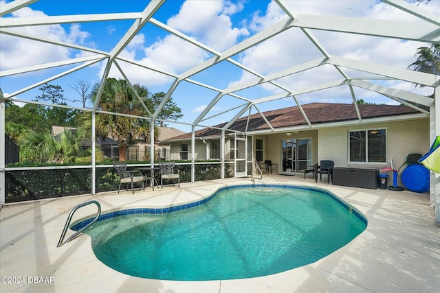 view of pool with glass enclosure and a patio