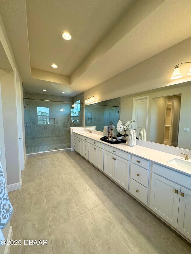 bathroom with a raised ceiling, vanity, and walk in shower