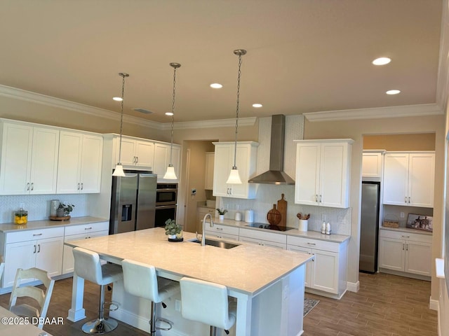 kitchen featuring decorative light fixtures, sink, stainless steel fridge, and wall chimney exhaust hood