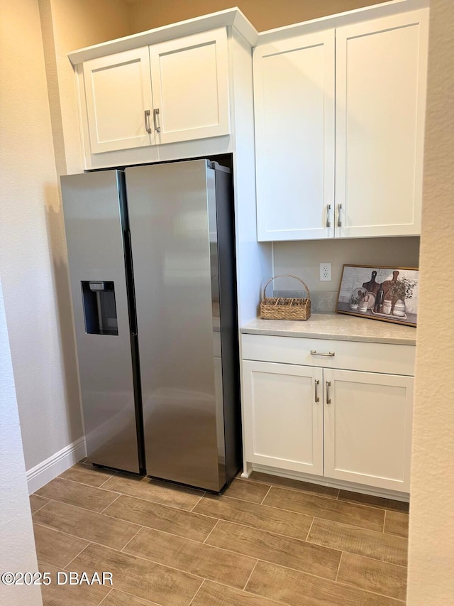 kitchen featuring stainless steel refrigerator with ice dispenser and white cabinets