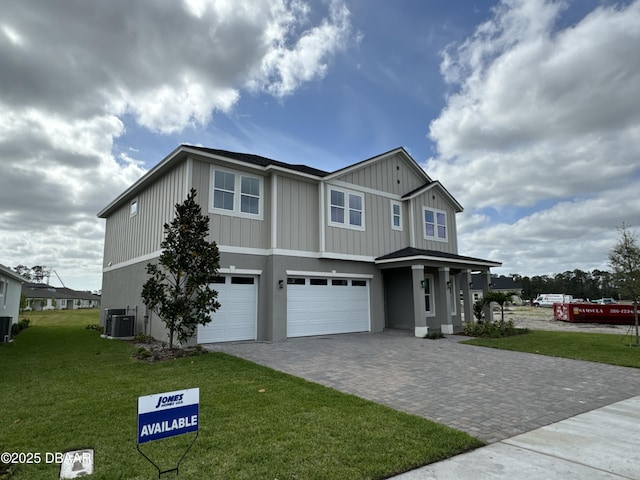 view of front of house featuring a garage, central AC unit, and a front lawn