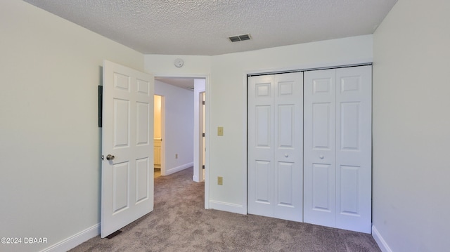 unfurnished bedroom featuring light carpet, a closet, and a textured ceiling