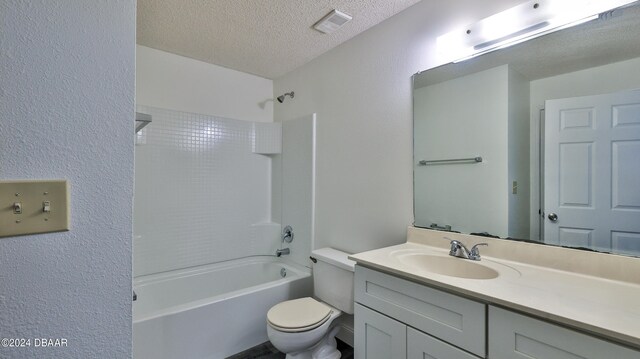 full bathroom with tiled shower / bath combo, vanity, a textured ceiling, and toilet