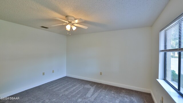 carpeted empty room featuring ceiling fan, a healthy amount of sunlight, and a textured ceiling