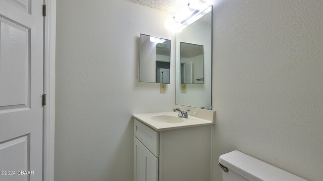 bathroom featuring toilet, vanity, and a textured ceiling