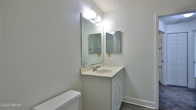 bathroom with vanity, a textured ceiling, and toilet