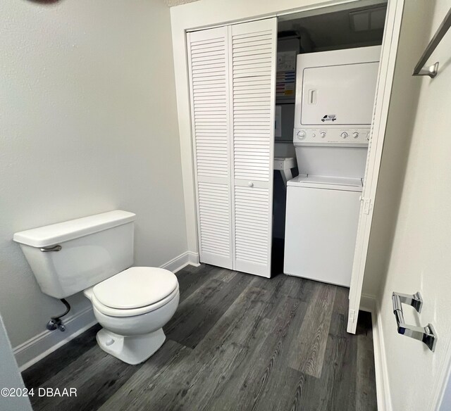 bathroom featuring toilet, hardwood / wood-style flooring, and stacked washer / drying machine