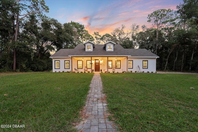 new england style home featuring a lawn and covered porch